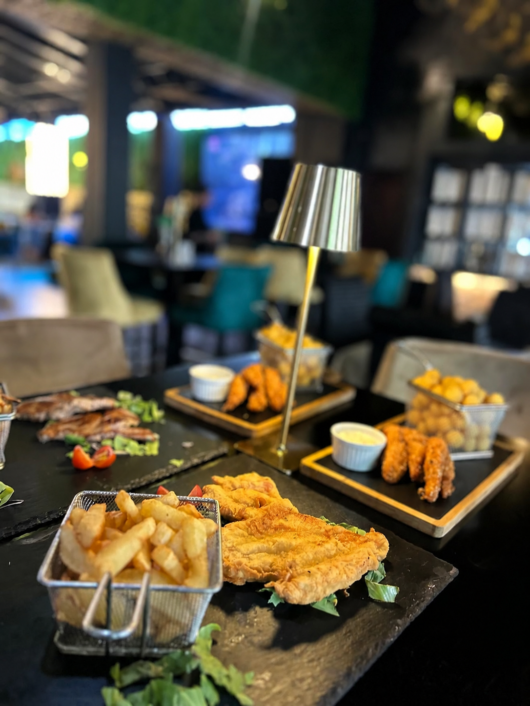 Plăci cu pește prăjit și garnitură de cartofi prăjiți, servite într-un restaurant elegant.