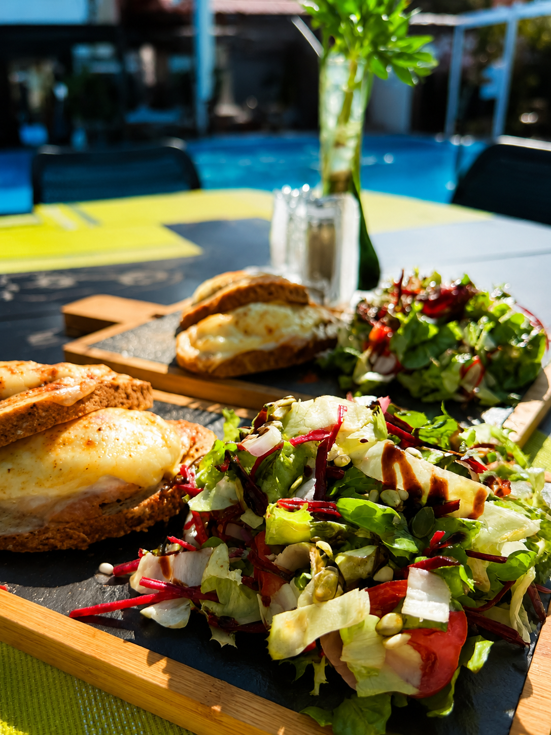 Sandwichuri de pui cu salată proaspătă, servite la o masă lângă piscină, într-o ambianță relaxantă de vară.
