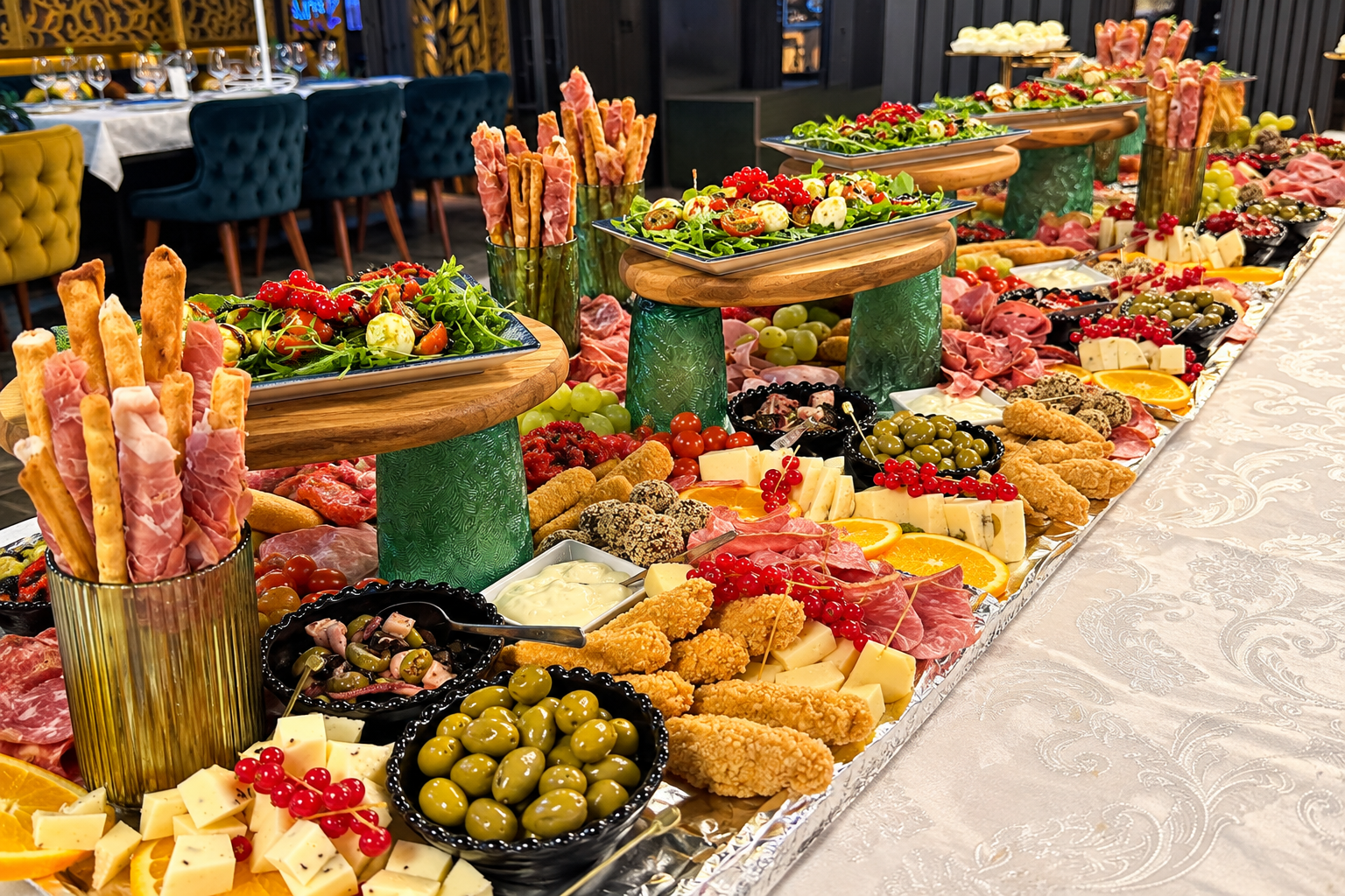 Plată cu brânzeturi, mezeluri, legume și aperitive pe o masă elegantă, cu decor sofisticat.