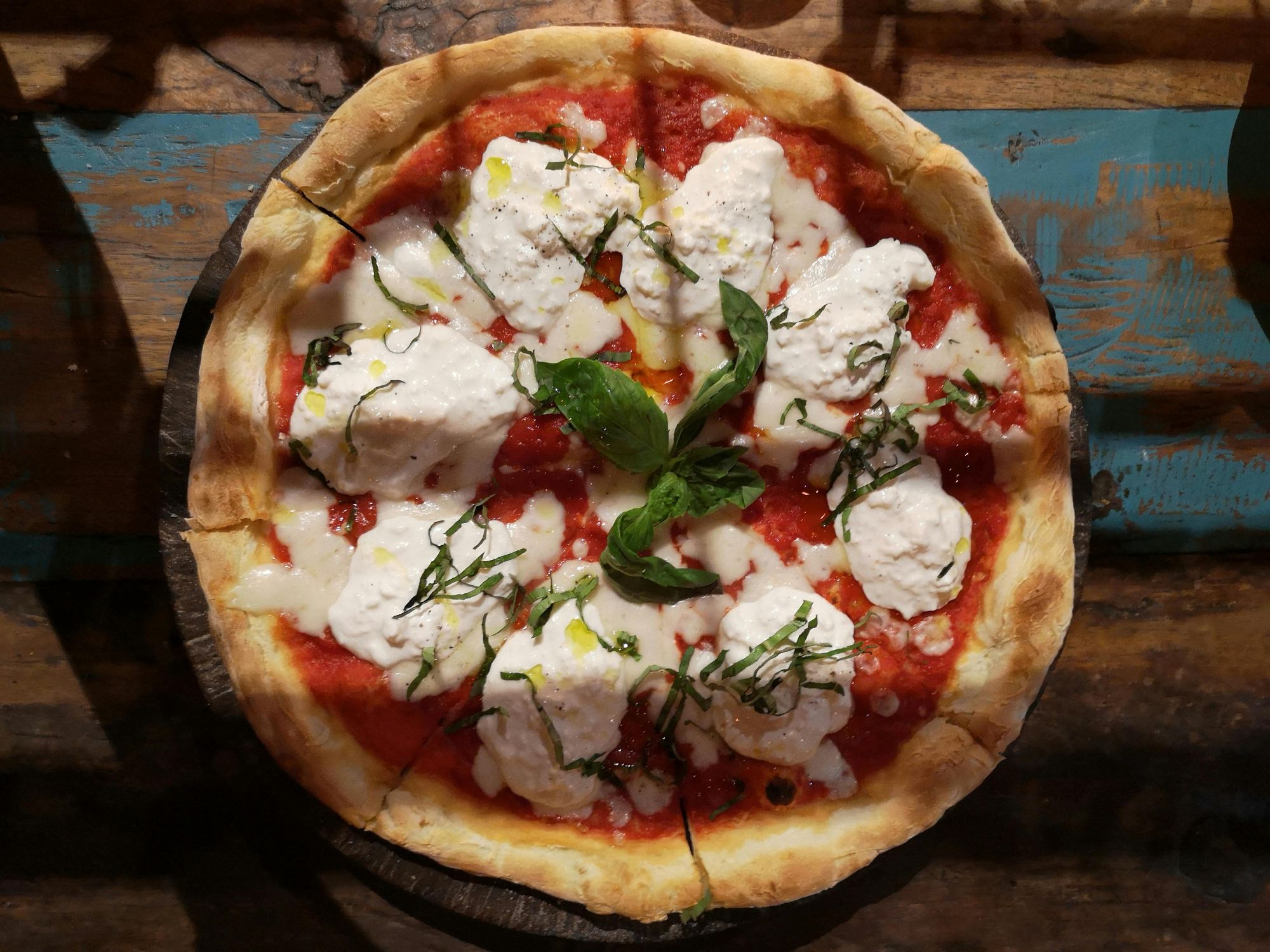 Pizza Margherita z serem ricotta, sosem pomidorowym, świeżą bazylią na drewnianej desce.