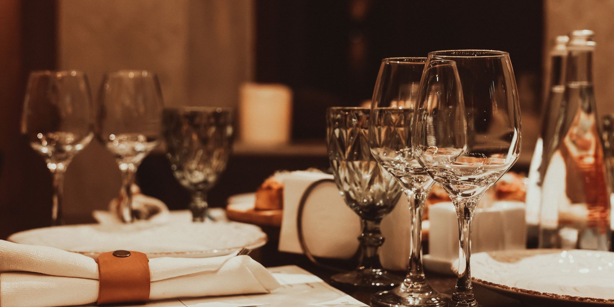 Elegancko ustawiony stół z kieliszkami, serwetkami i butelkami w przytulnej restauracji.