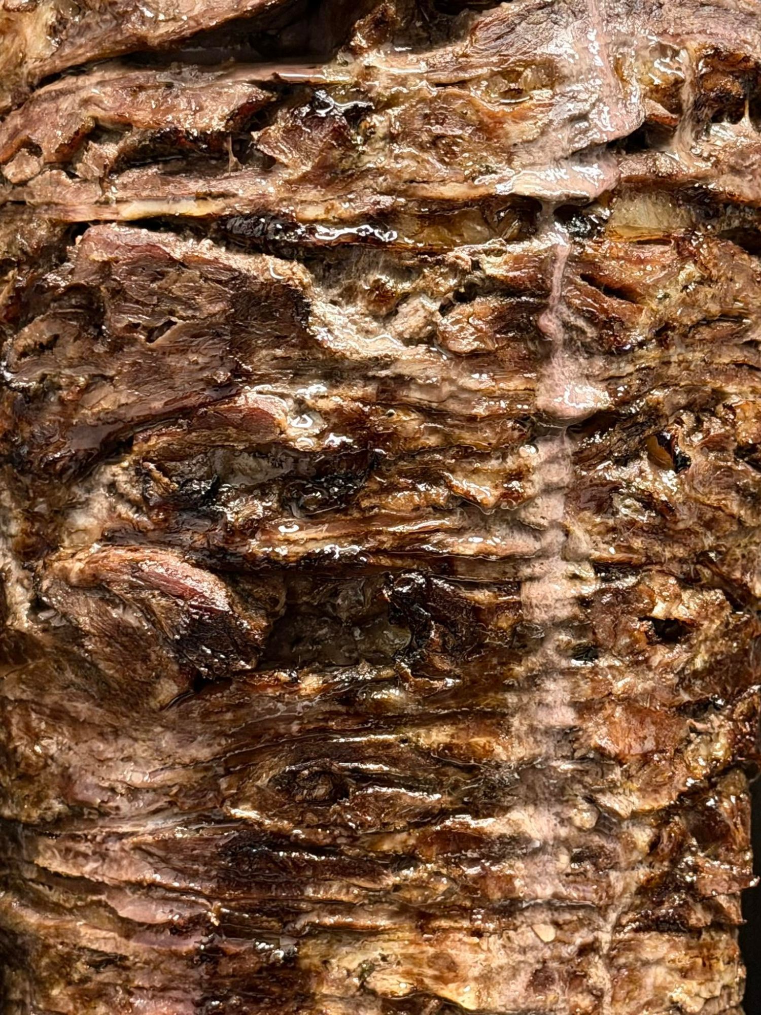 Tekstura mięsa w stylu kebab, z wyraźnymi smugami przypalenia i różnorodnymi odcieniami brązu.