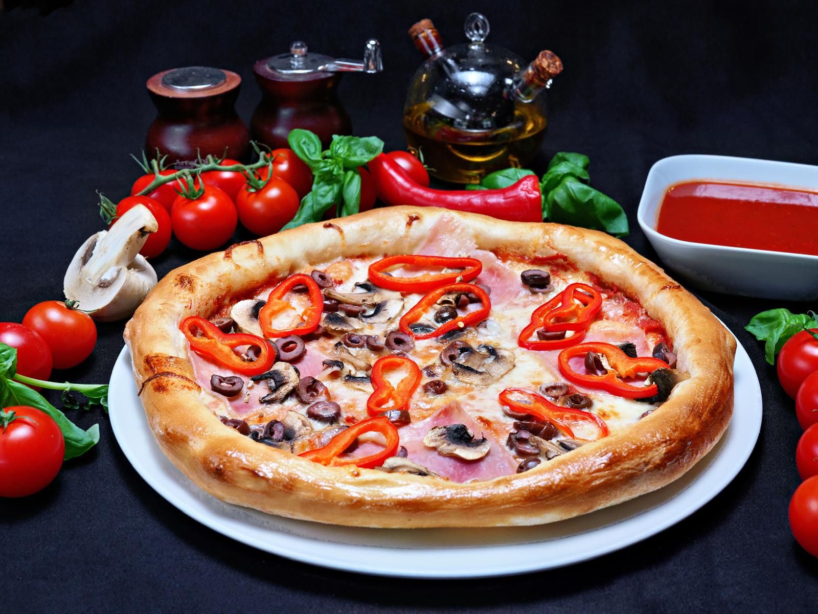 Pizza delicioasă cu ciuperci, ardei roșii și roșii proaspete, servită pe un fundal negru.