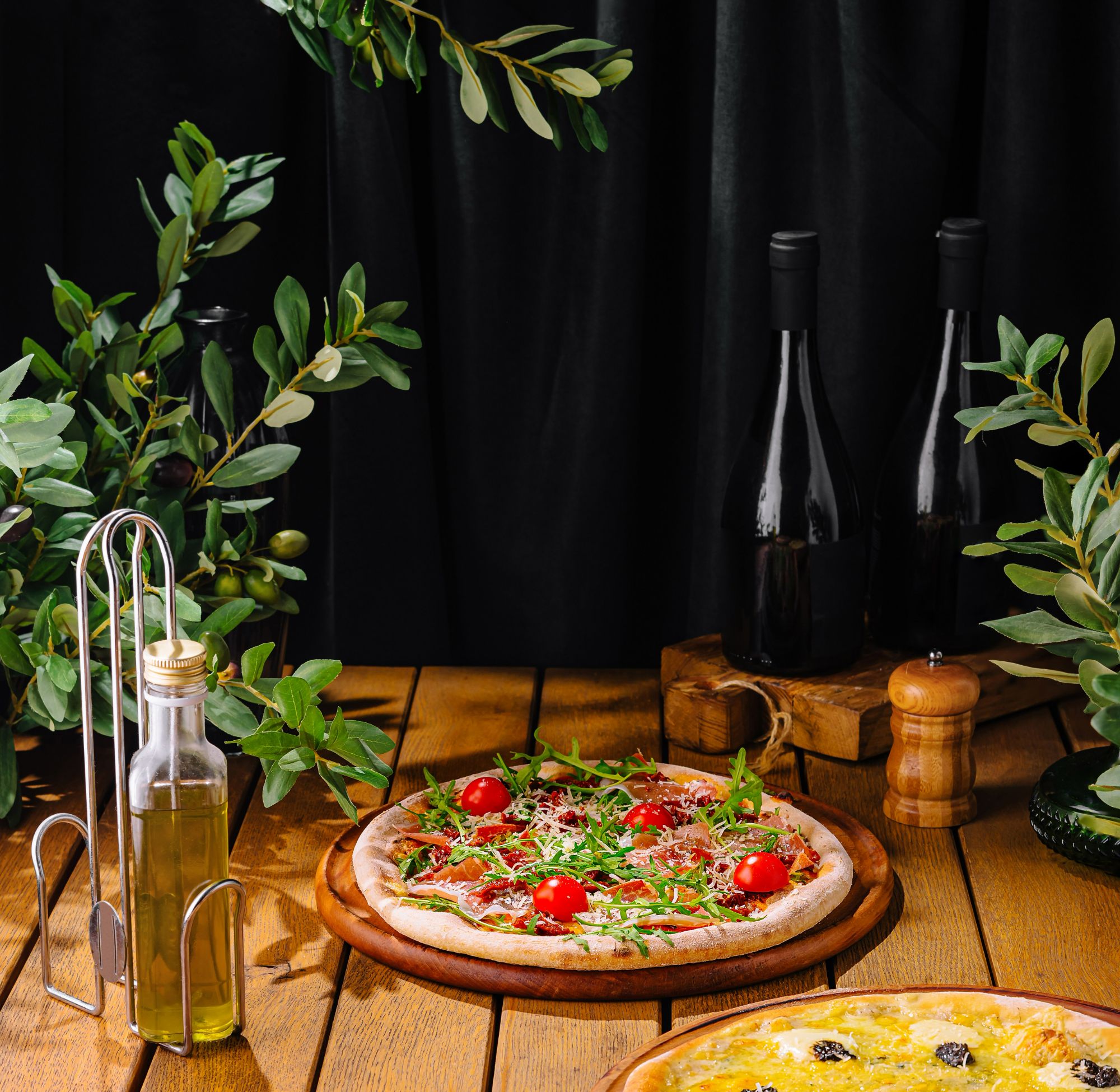 Pizza z pomidorami i rukolą, oliwa z oliwek, wino i zioła na drewnianym blacie.