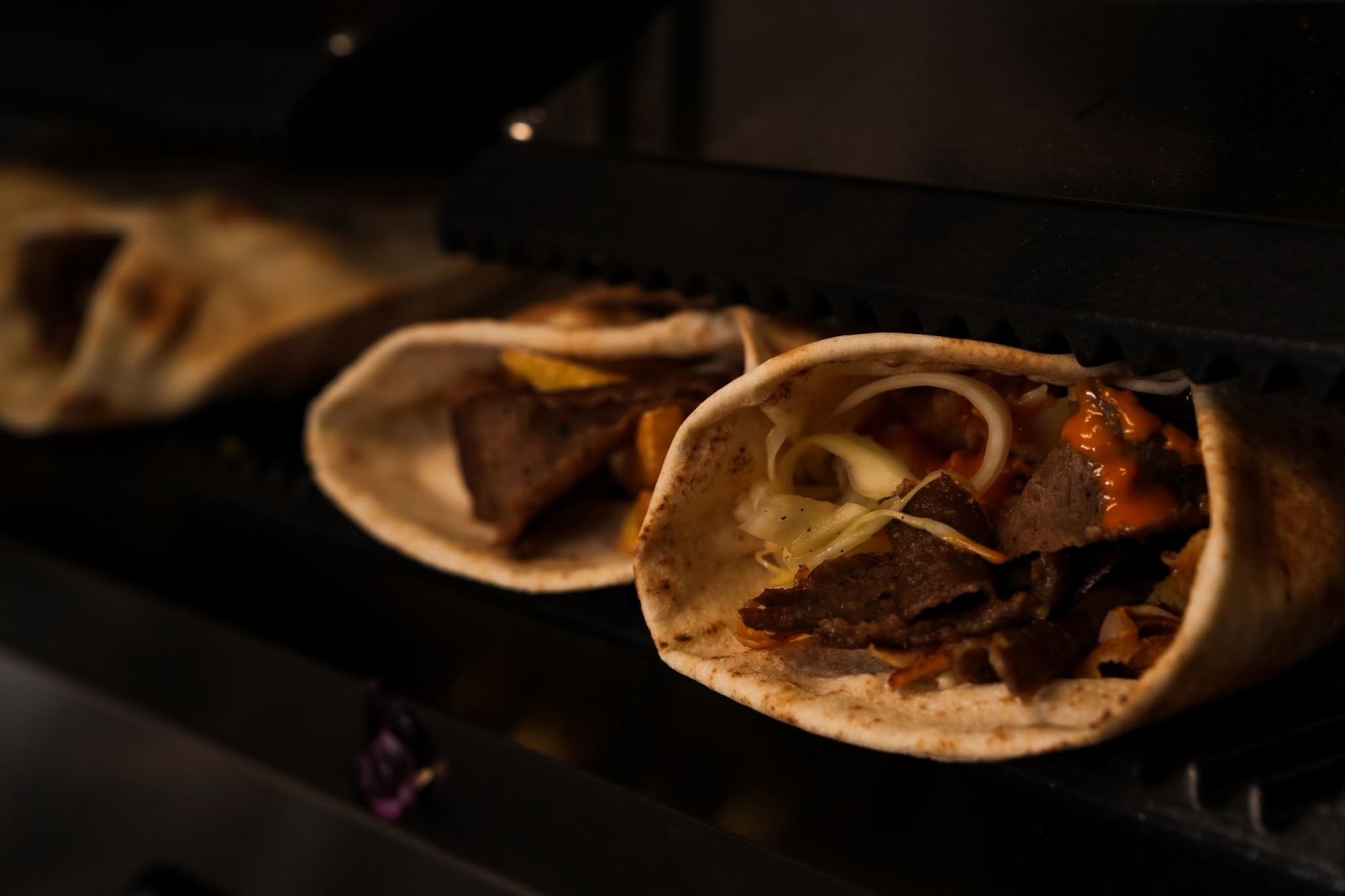 Tortilla wypełniona mięsem, sosami i warzywami, świeżo podawana na grillu.