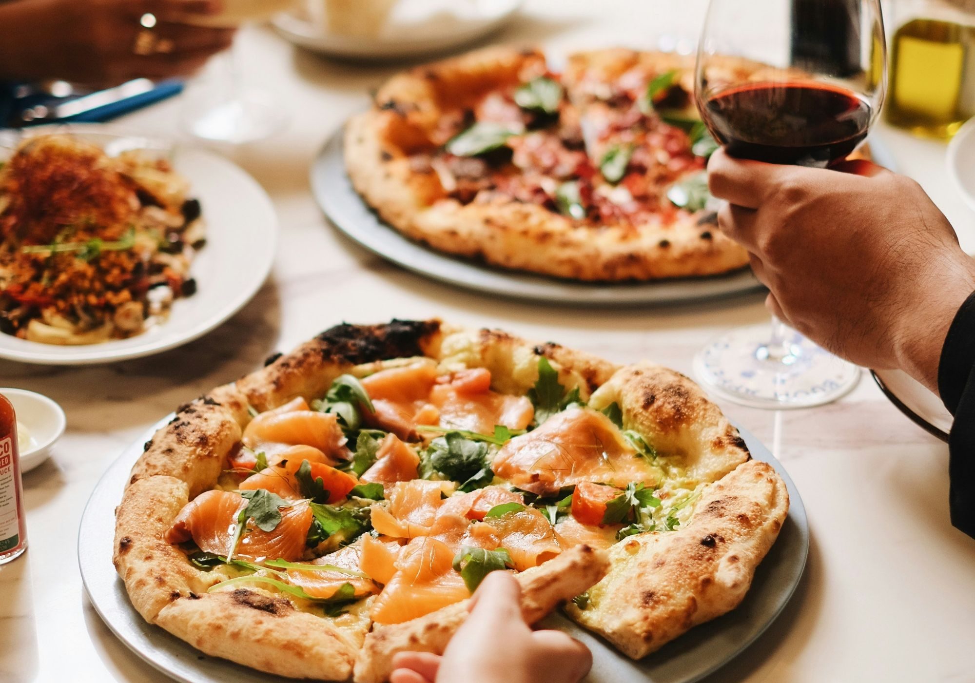Zbliżenie na stół z pizzą, sałatką i winem, idealne na spotkanie przy jedzeniu dzielonym.