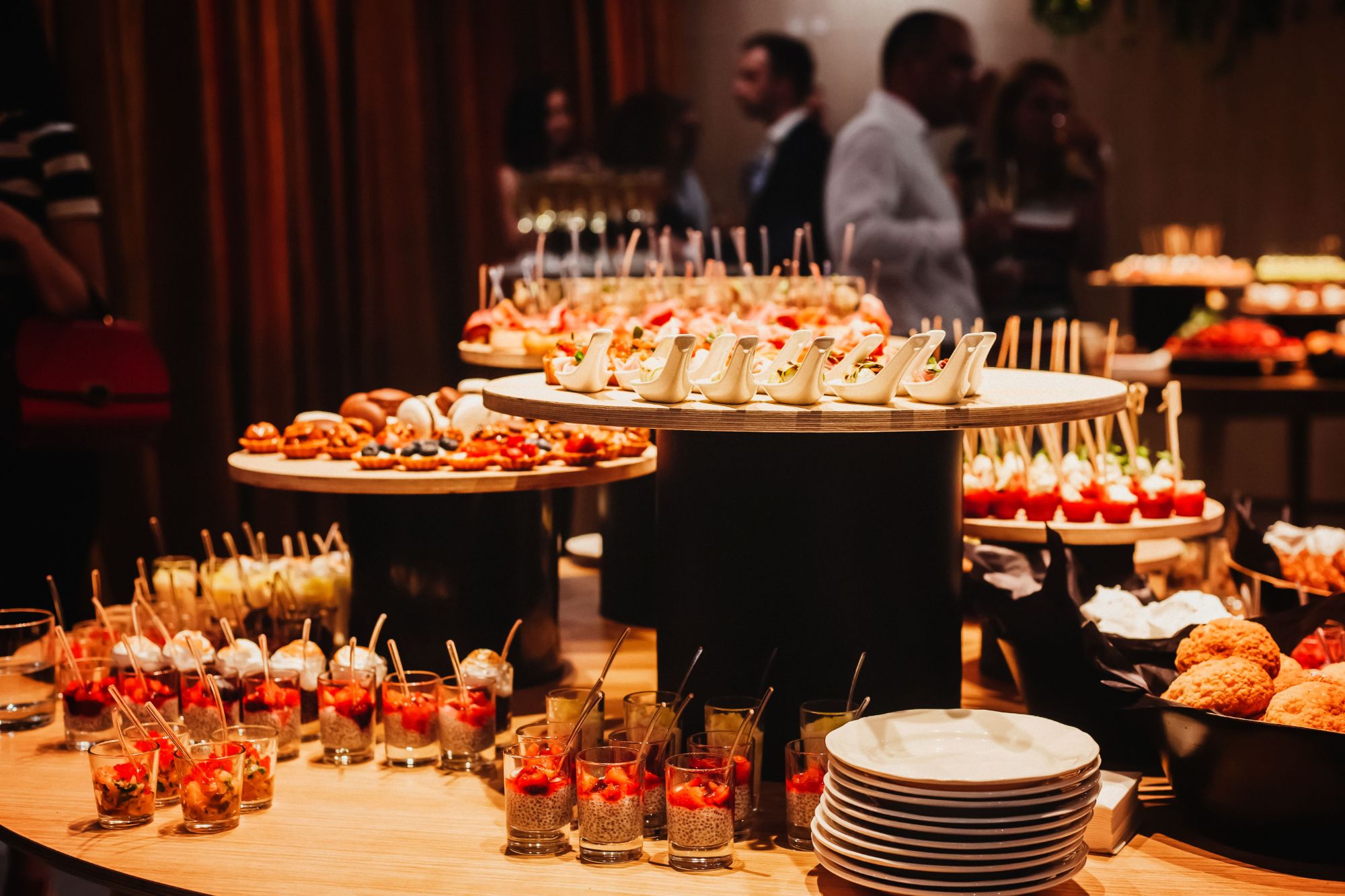 Tavă cu aperitive elegante, deserturi variate și băuturi, la un eveniment sofisticat.