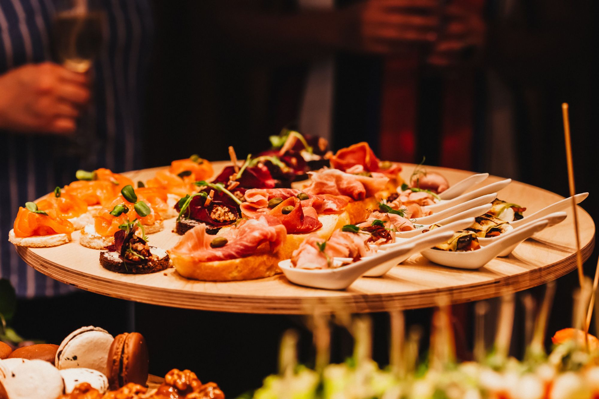 Platou cu aperitive diverse, incluzând bruschete, sushi și delicatese, pe un fundal festiv.