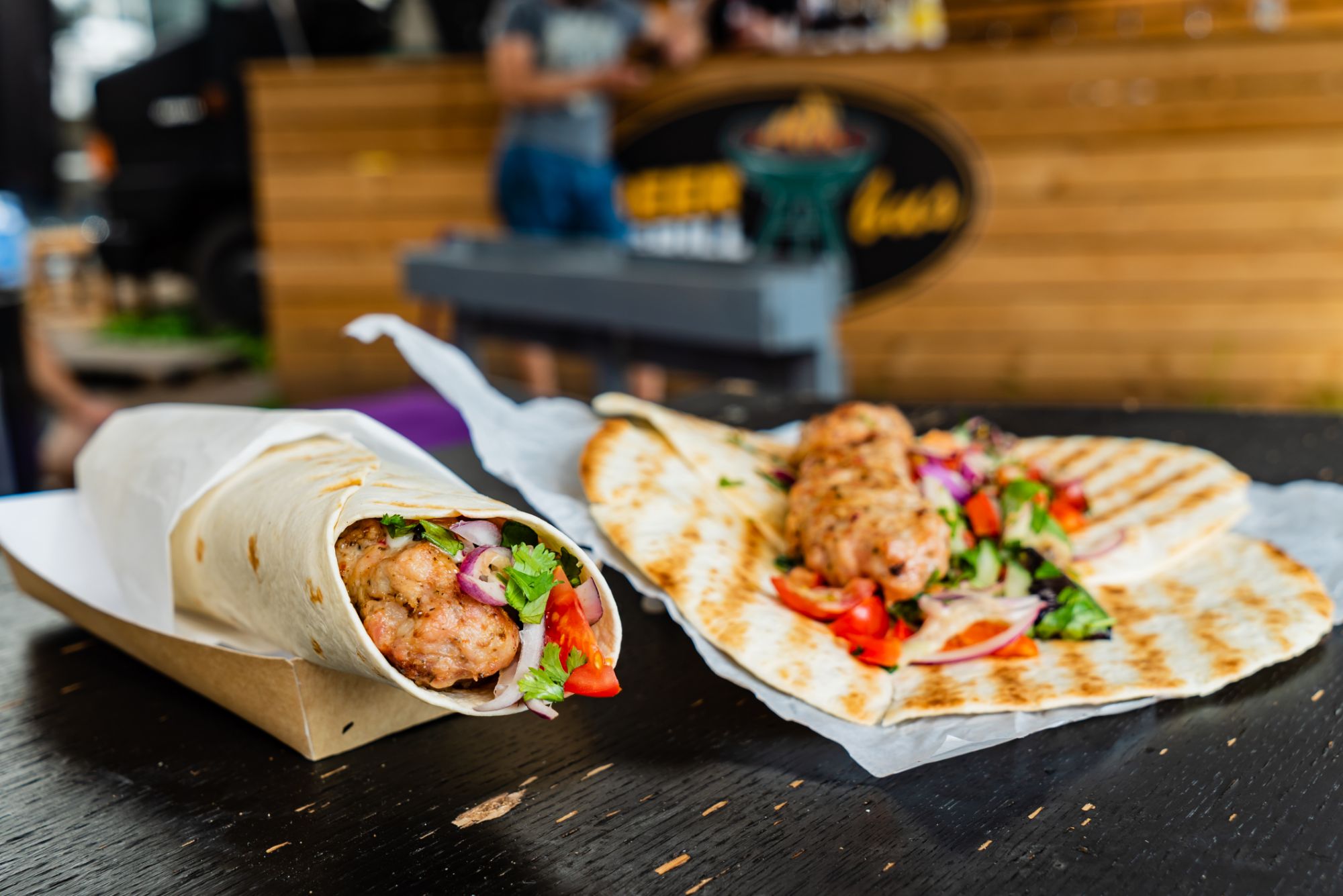 Tortilla z nadzieniem warzywnym i kurczakiem obok podgrzanej tortilli z sałatą, pomidorami i cebulą.