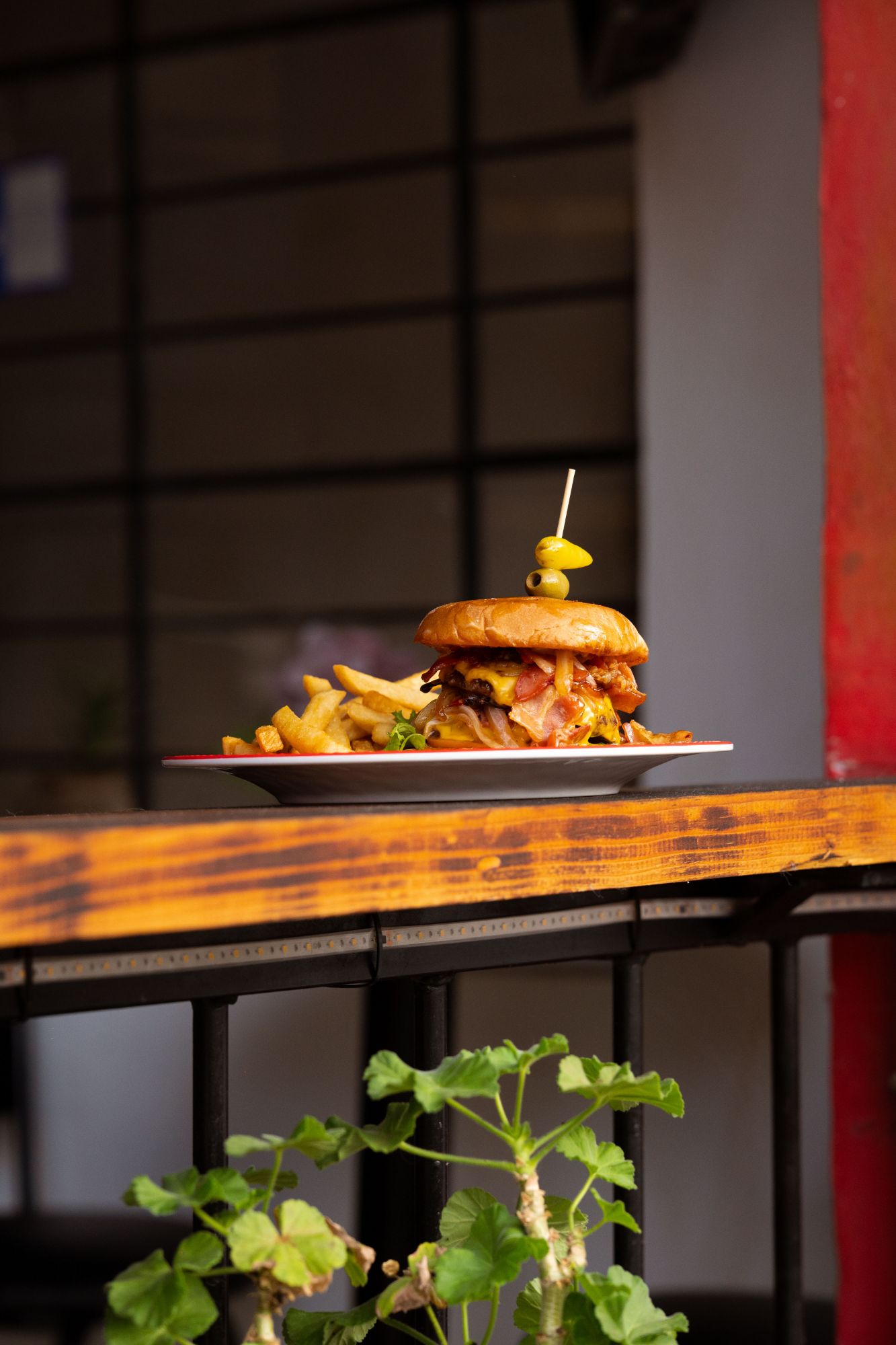 Burger z bekonem i frytkami, podany na drewnianym stole w restauracji.