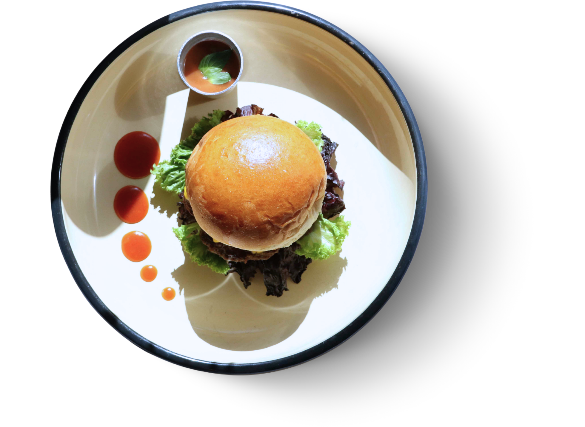 Burgery na talerzu z sałatą, ketchupem i sosem w małej miseczce.