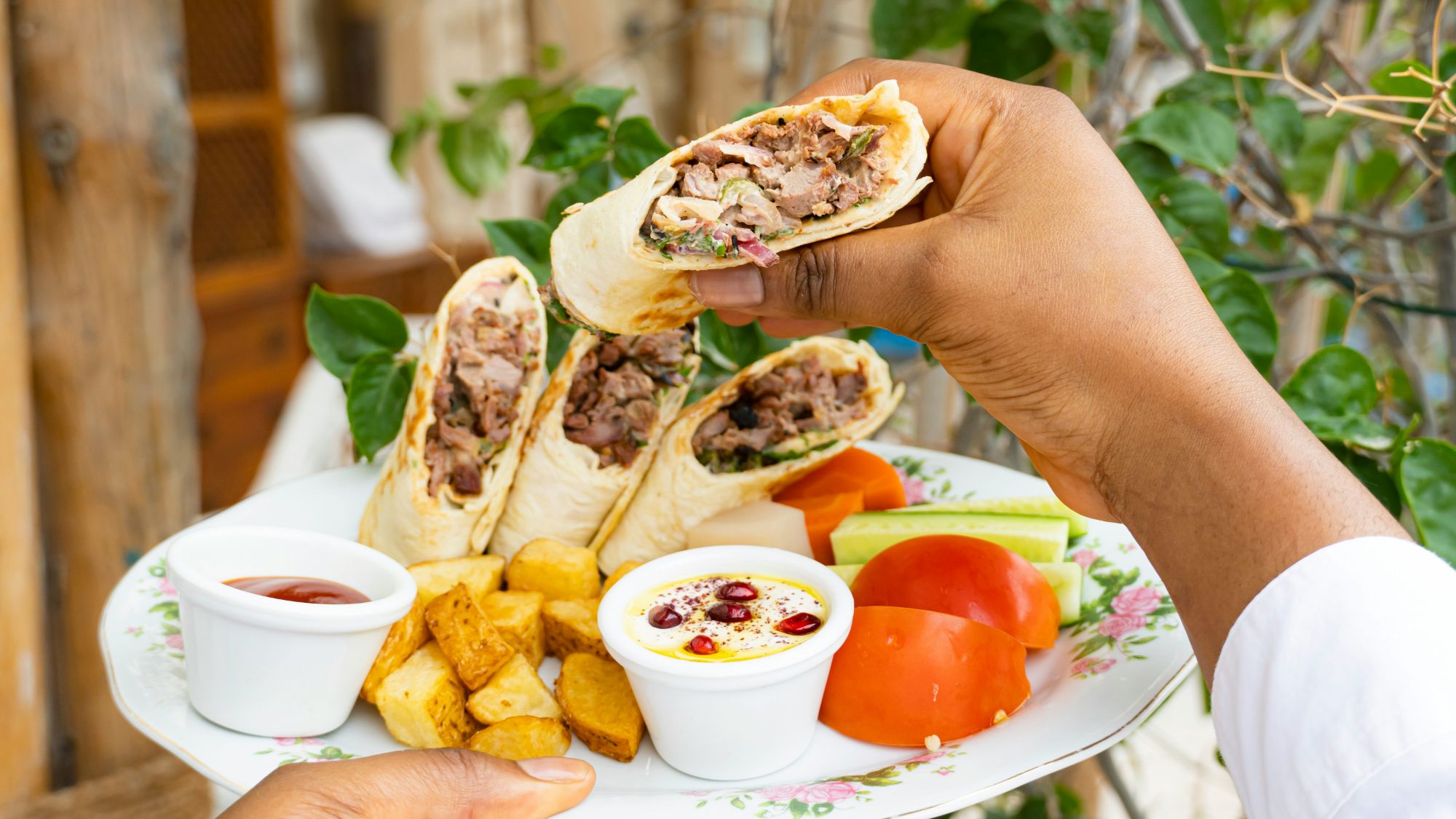 Talerz z burrito z mięsem, frytkami, warzywami i sosami w tle.