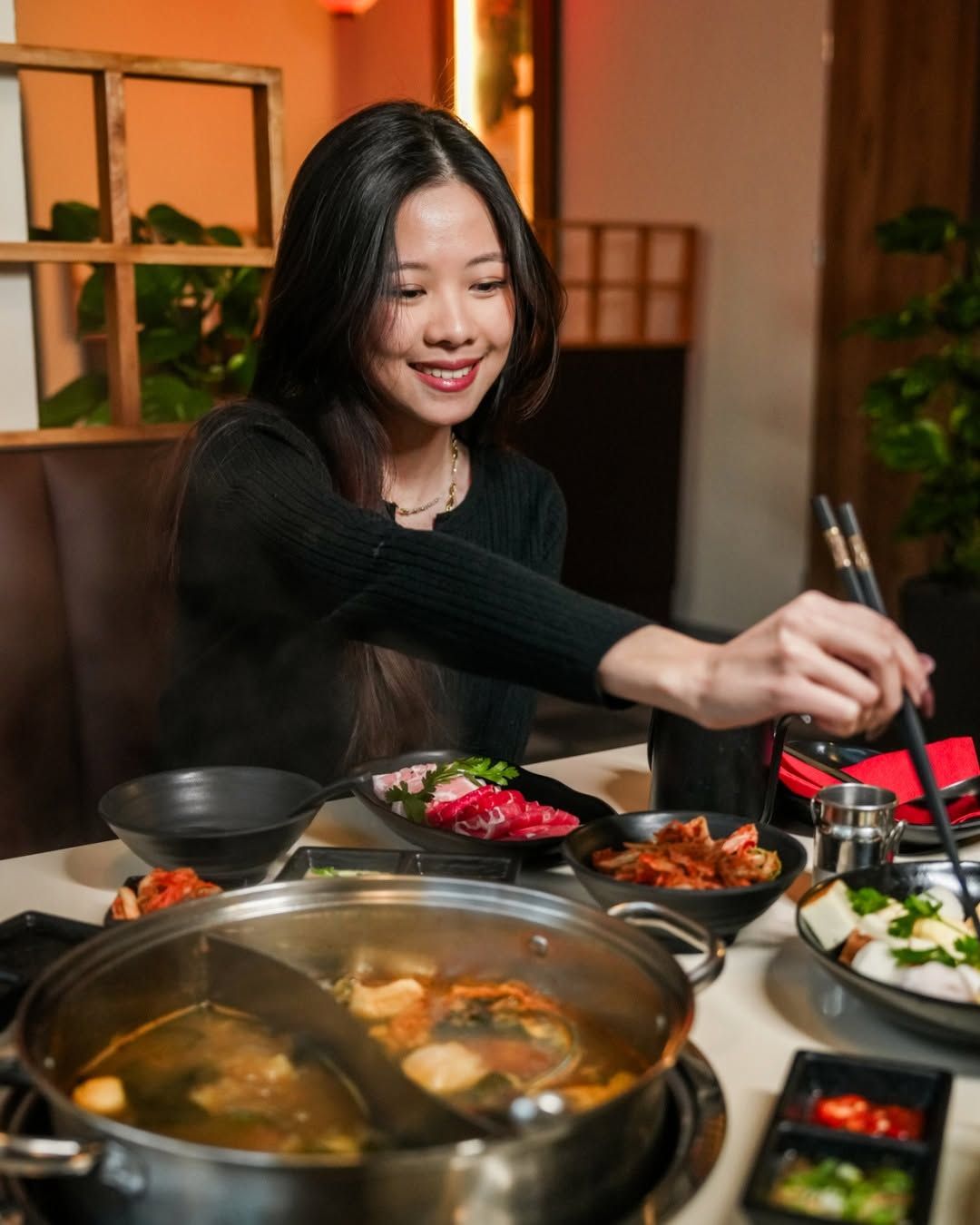 Kobieta w restauracji korzystająca z pałeczek, serwująca jedzenie z gorącego garnka.