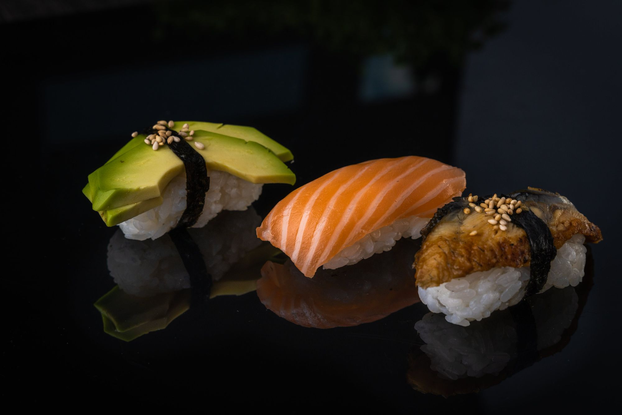 Trzysta kawałków sushi: łosoś, awokado i węgorz, podane na czarnym tle.