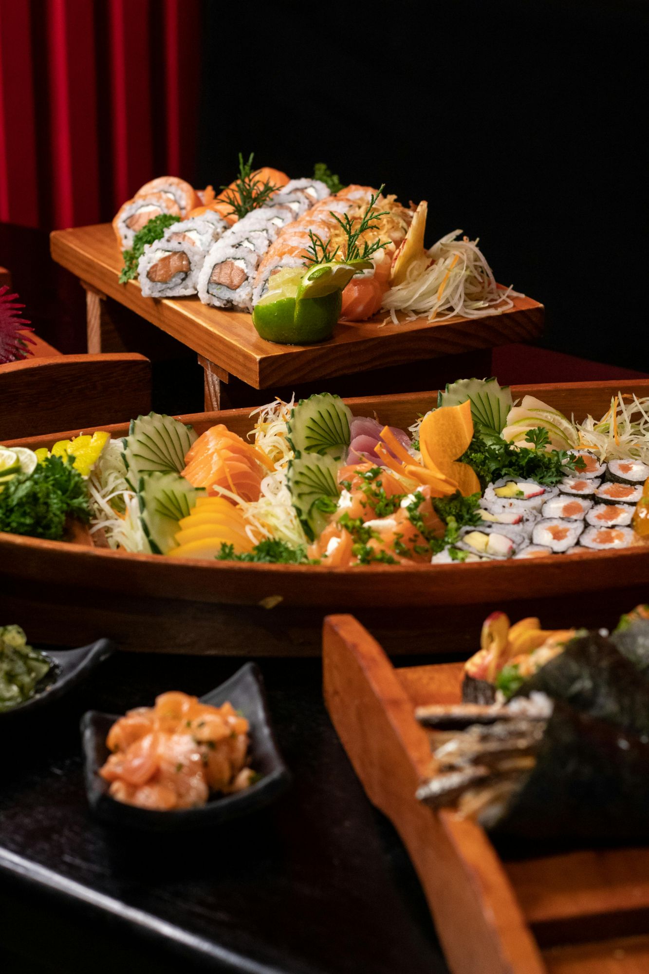Stylowe talerze sushi z różnorodnymi kawałkami ryb i owocami morza, podane na ciemnym tle.
