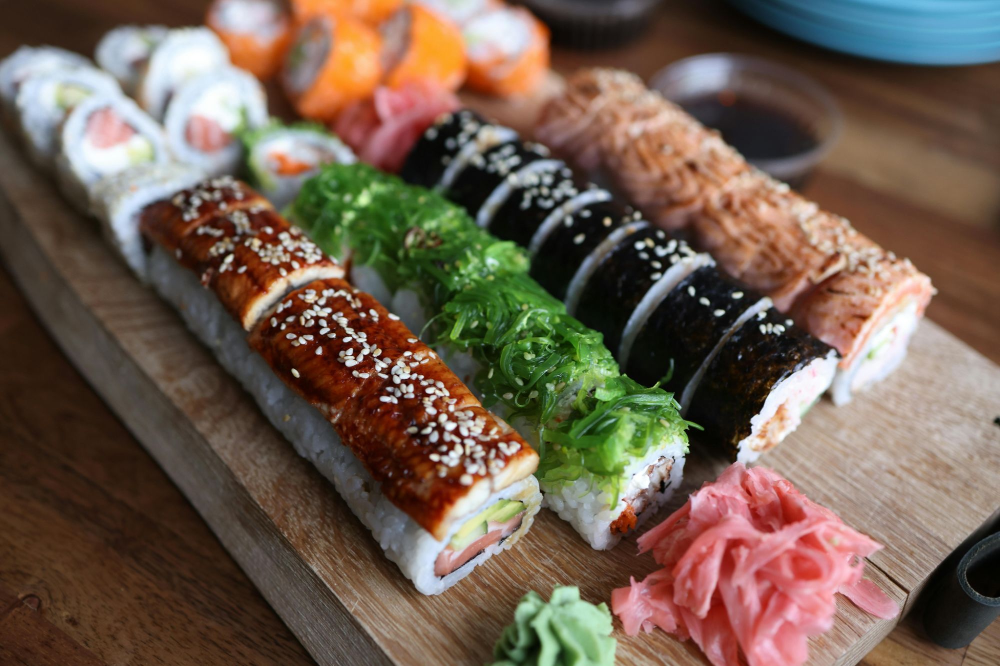 Sushi na desce, różnorodne rodzaje z rybą, warzywami, imbirem i chrzanem wasabi.