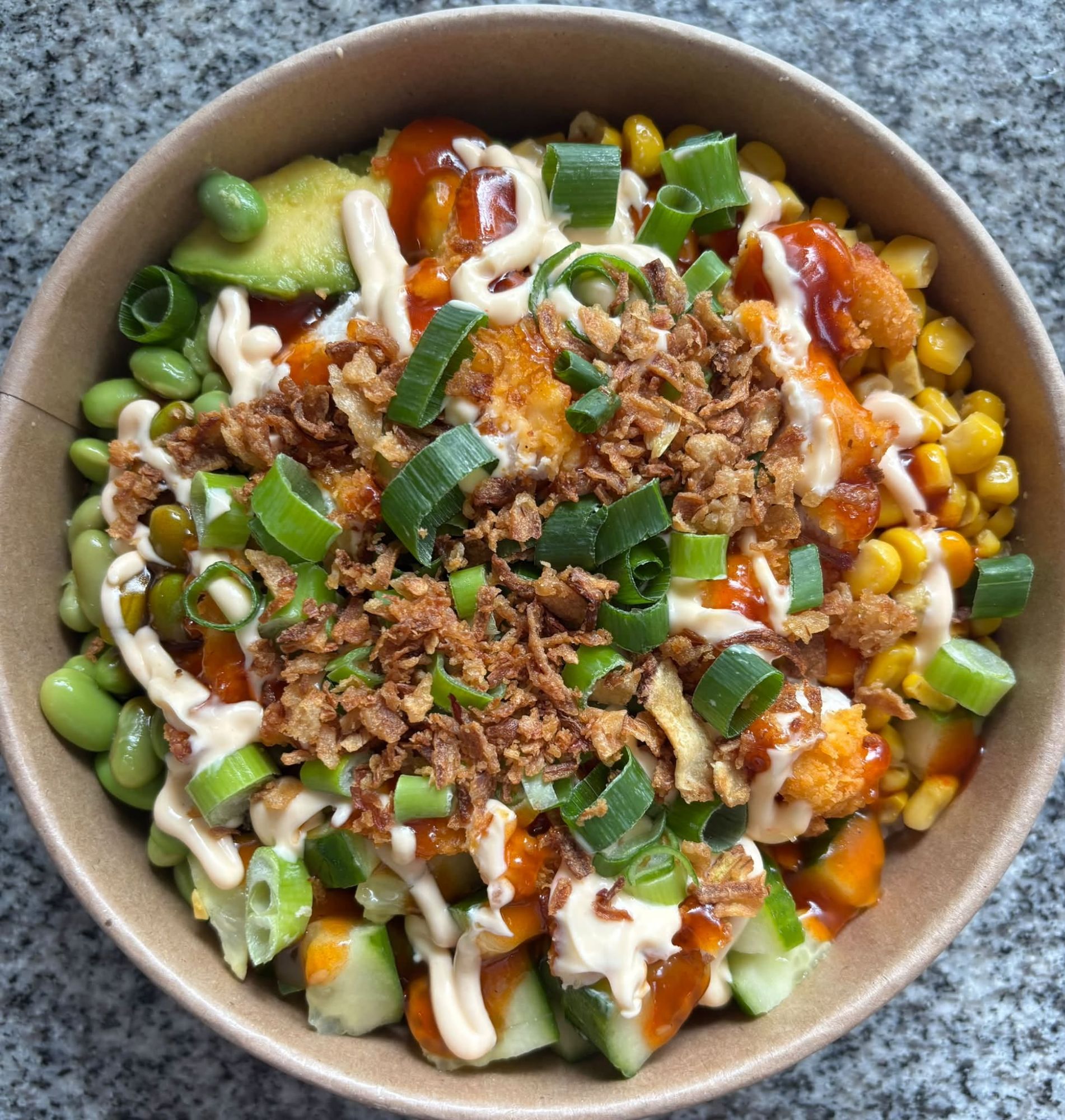 Miska sałatkowa z awokado, kukurydzą, edamame, ogórkiem, sosem, szczypiorkiem i chrupiącą cebulką.