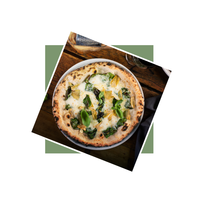 Pizza z serem, szpinakiem i ziołami na drewnianym stole.